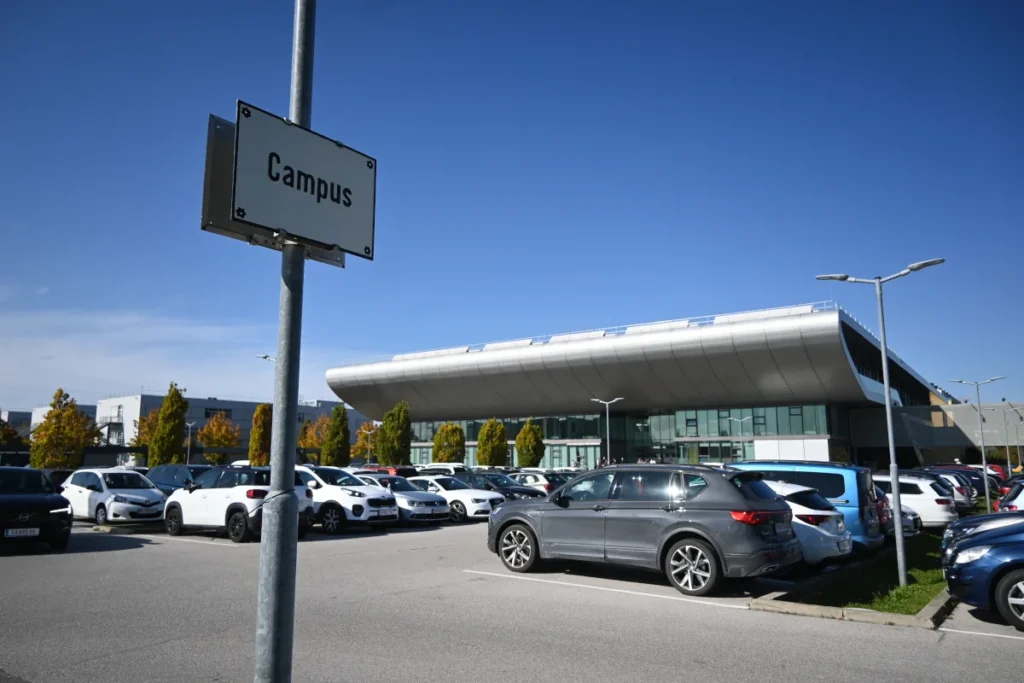 A sign saying "Campus" in front of the parking lot and the main building