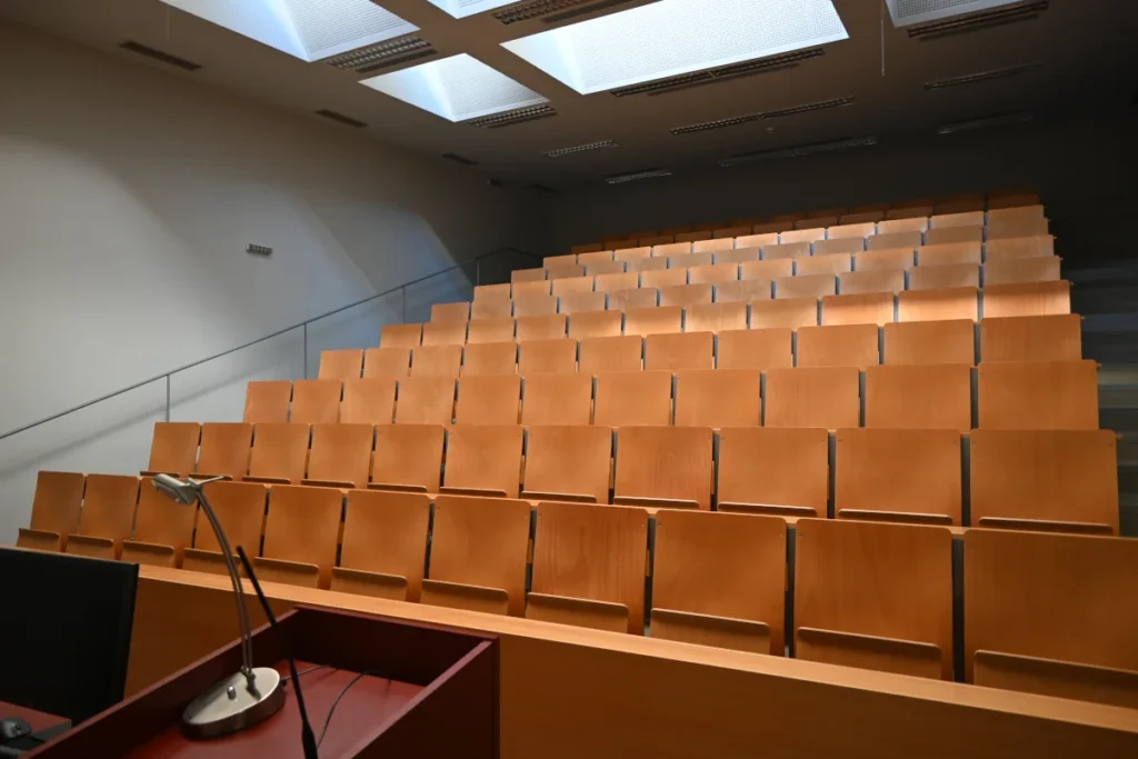 Rows of seats behind a speaker's desk with a desk lamp and a microphone